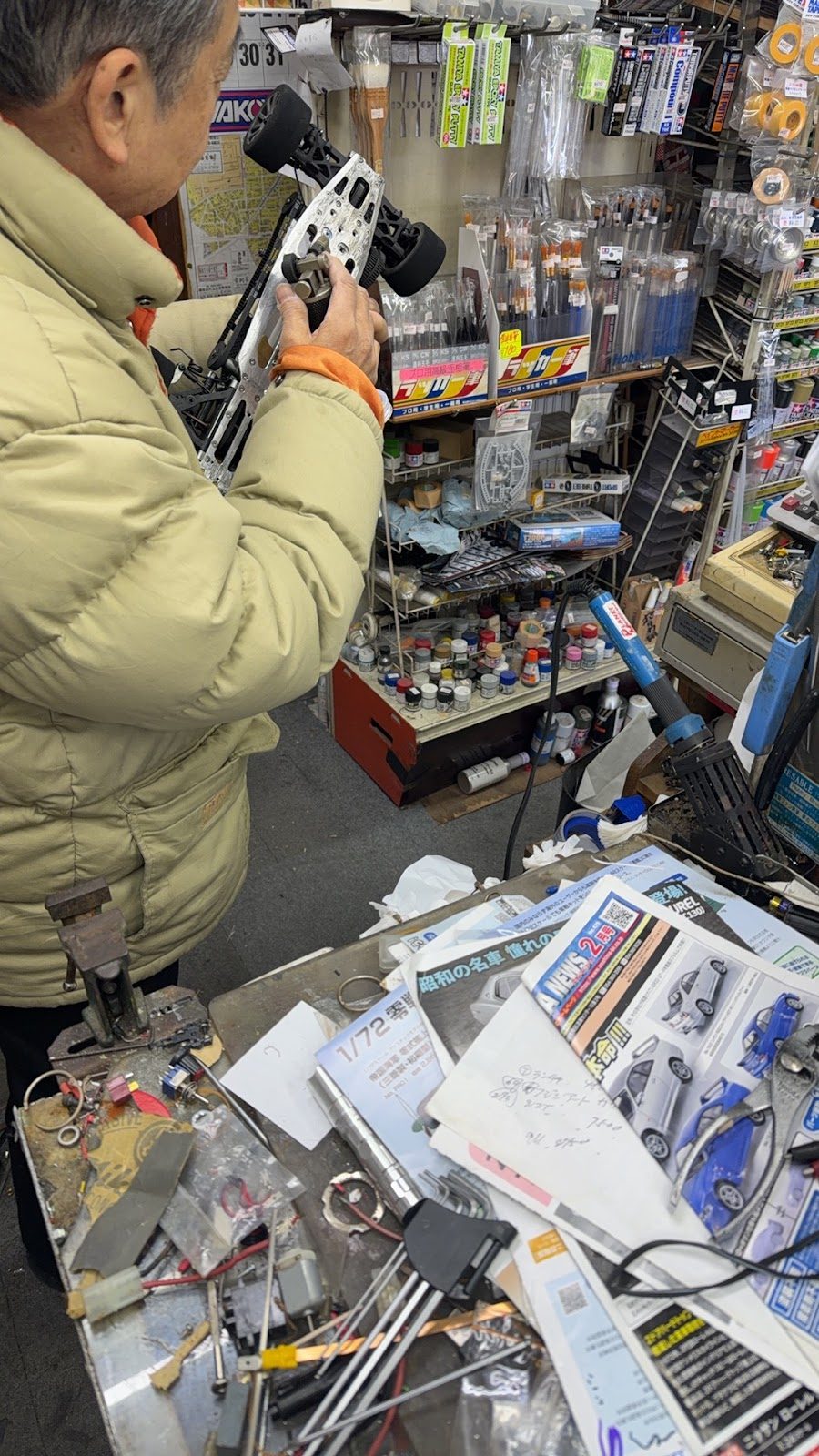 店内でラジコンカーを手に持つ男性と工具が並ぶ作業台