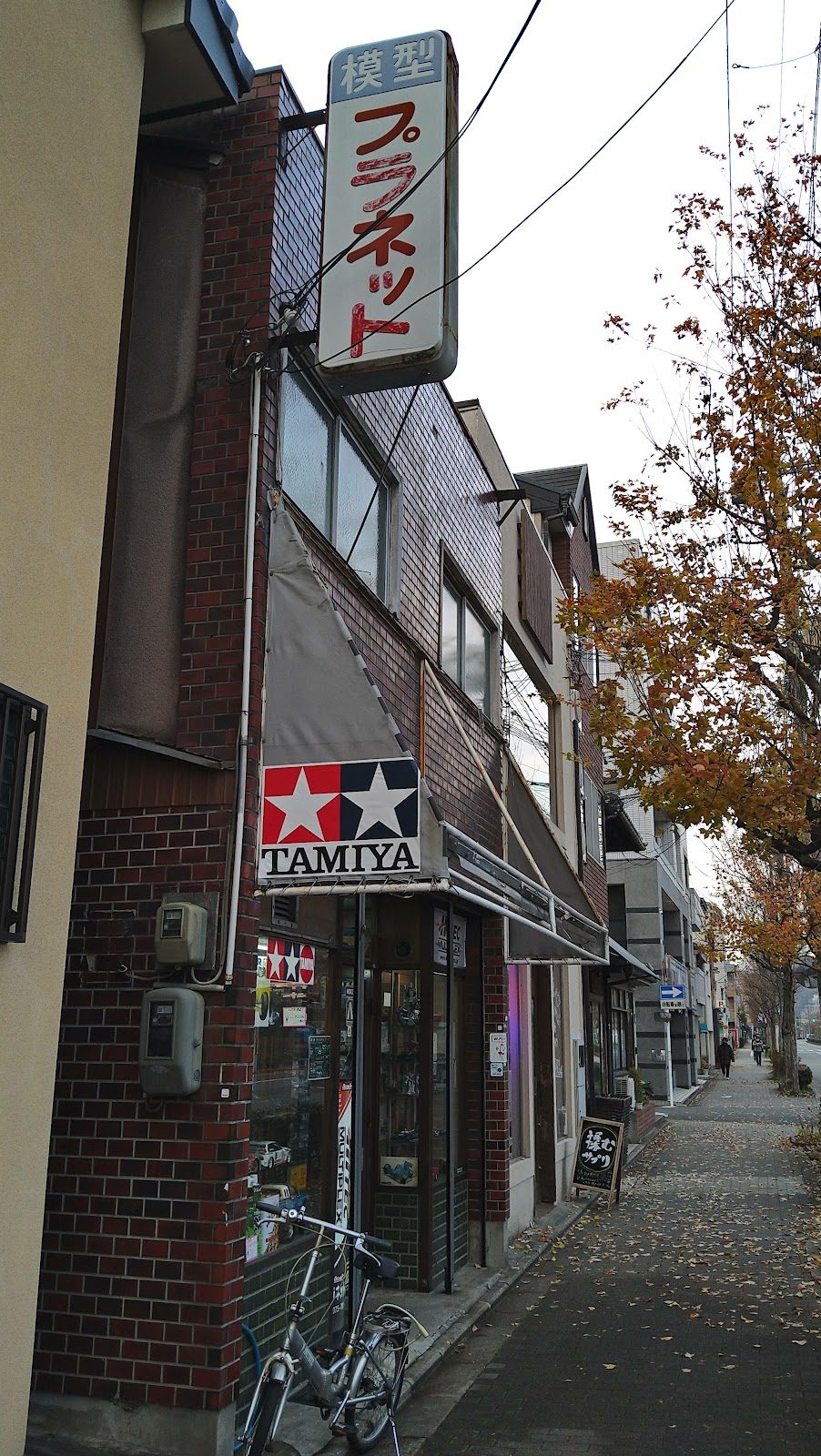 プラネット模型の看板とタミヤのロゴがある店舗外観と自転車