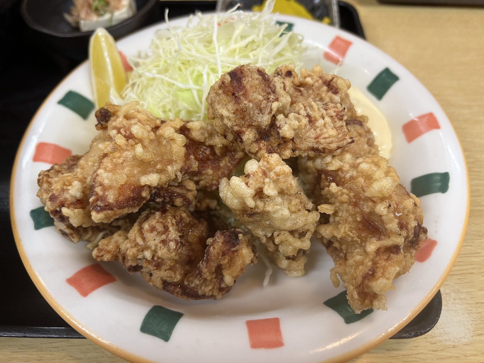 白い皿に盛られた揚げ物とキャベツ、レモンの付け合わせ