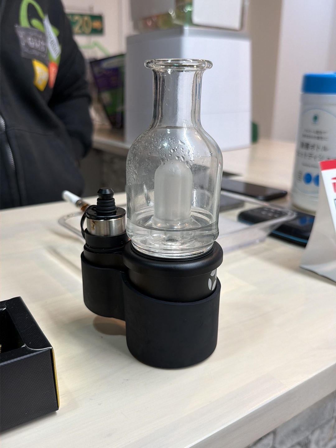 透明なガラス製のパイプと黒い容器が棚に並んでいる