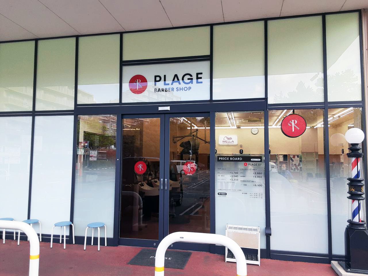 ガラス張りの店舗入口。PLAGEの看板と料金表、店内の椅子が見える