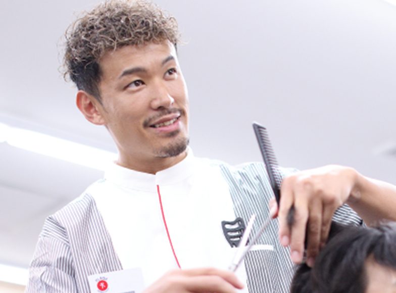 白衣を着た男性がハサミとコームで客の髪を切っている