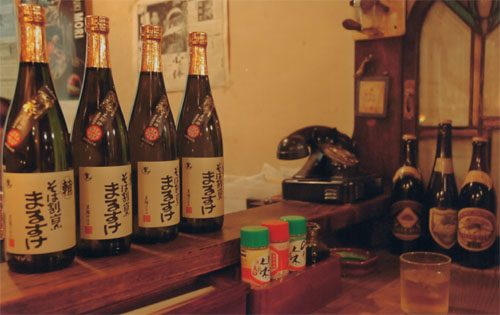黒いラベルの日本酒の瓶が多数並べられた店内の棚
