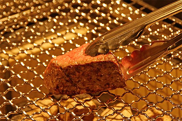 炭火で焼かれた肉料理が焼き網の上で調理されている様子
