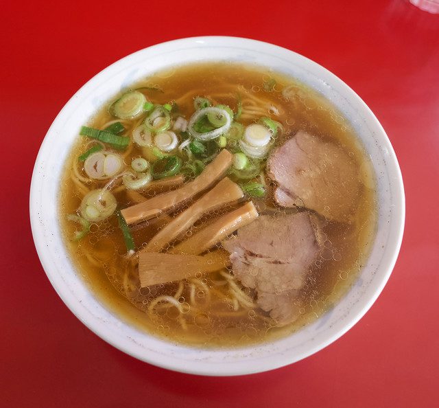 赤いテーブルに並んだ、ネギとメンマが乗った中華そばの丼