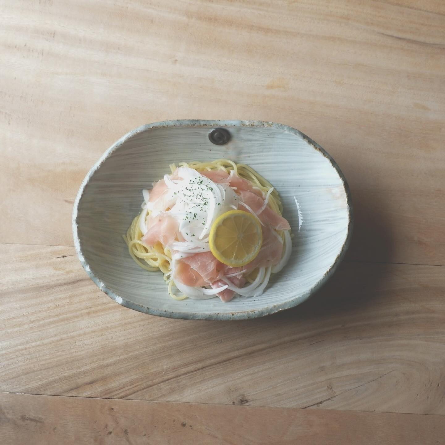 Kitchen Q|木のテーブルに置かれた、サラダを添えた料理の皿