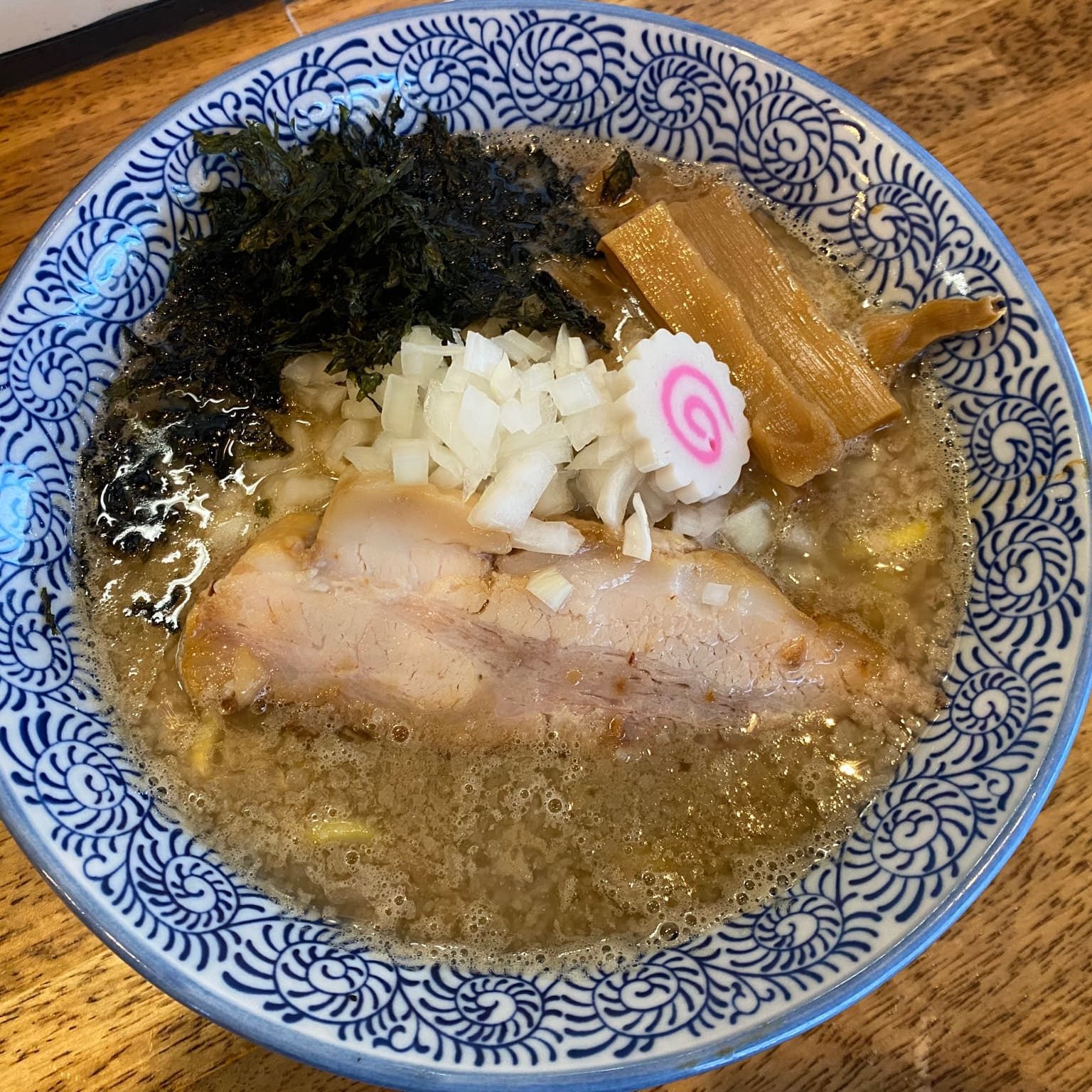 青い柄の器に盛られた麺料理と具材が写っている
