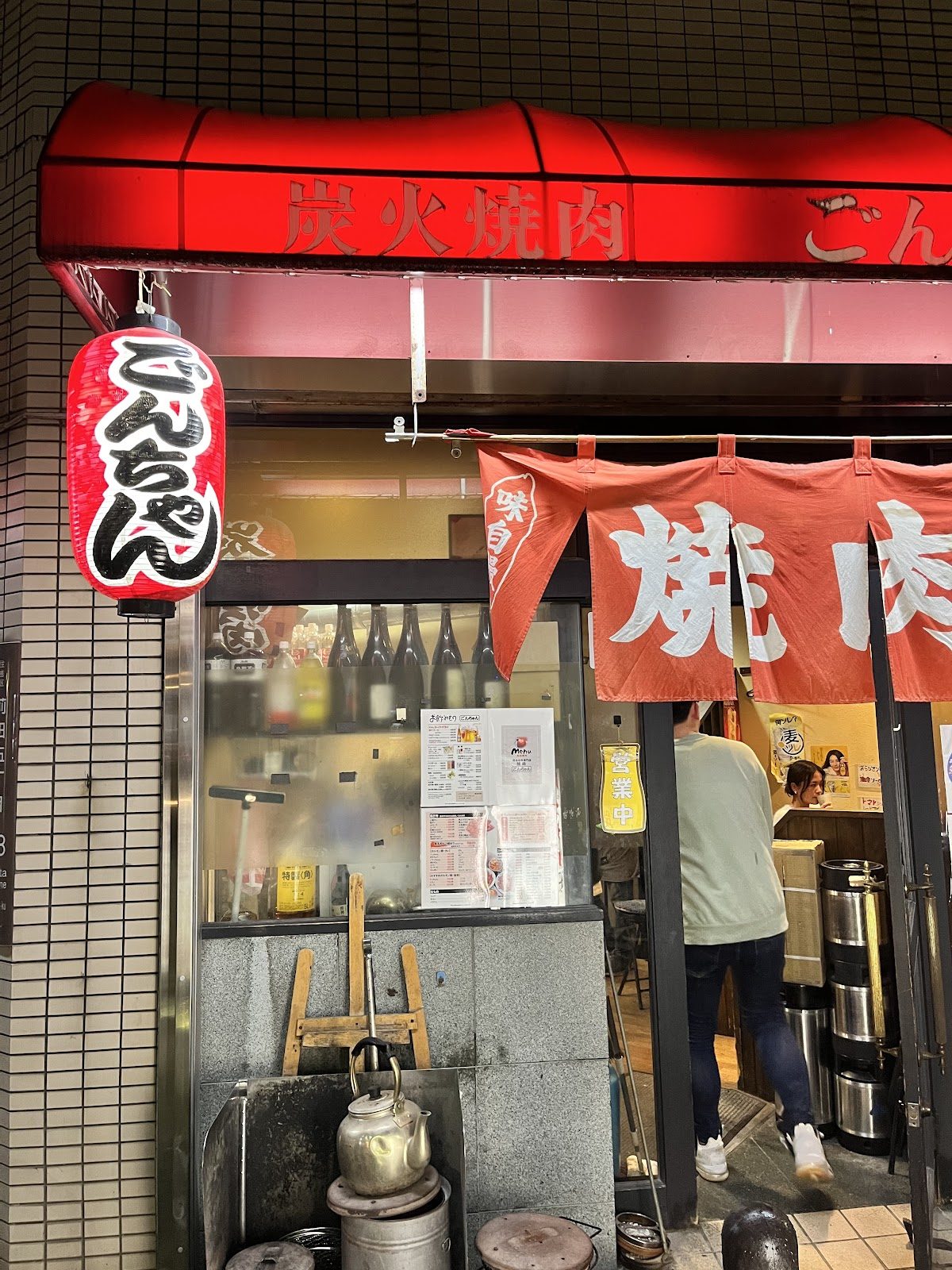 店内の壁に貼られた赤い「炭火焼肉」の文字と、客が食事をする様子