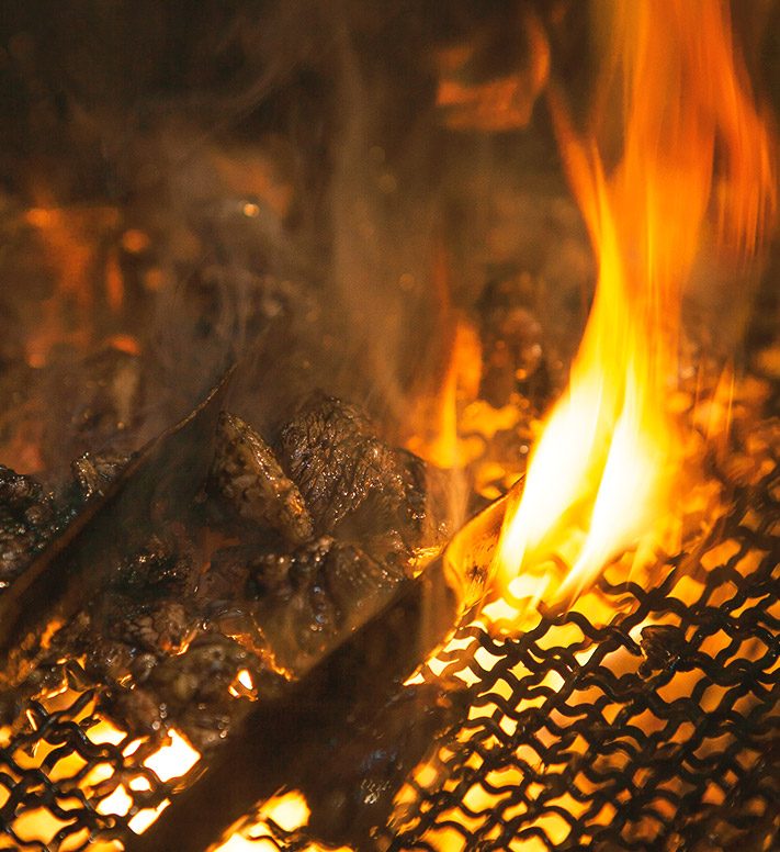 炭火で焼かれる焼き鳥の串が炎に照らされている様子
