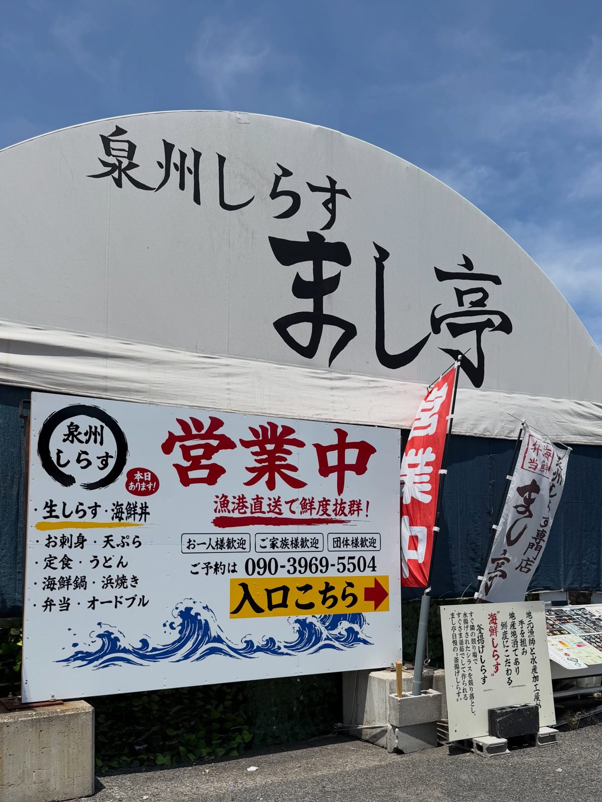店名が書かれた大きな白い屋根と、営業中の看板が写っている外観