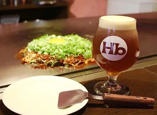 鉄板の上に広島焼きとビールグラスが置かれている