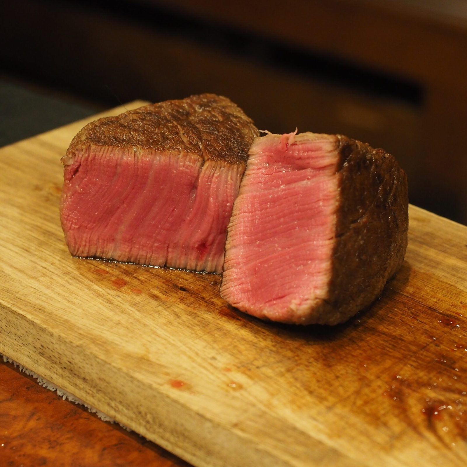 炭火で焼かれる赤身肉のステーキが並ぶグリルの様子